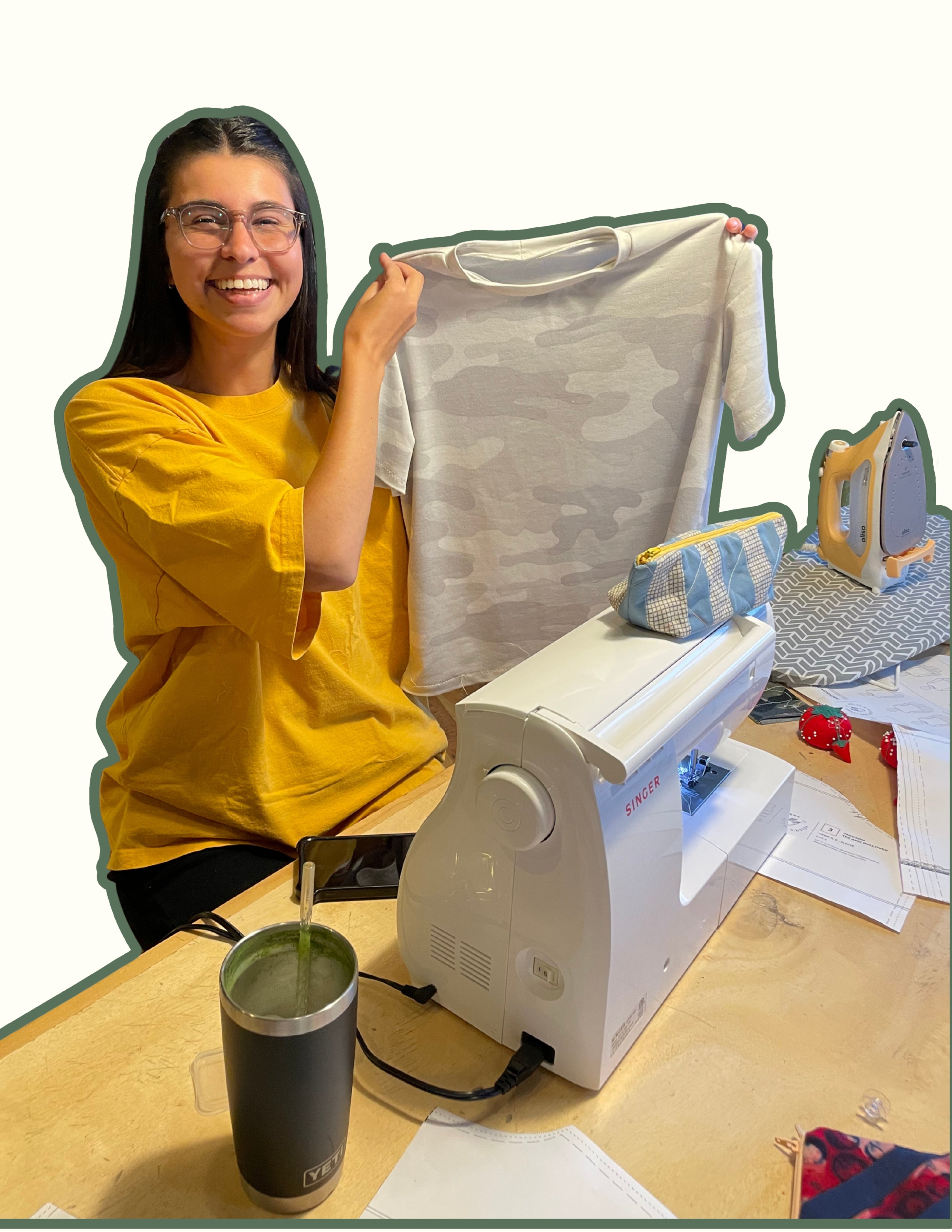 Person holding a shirt next to a sewing machine on a table.